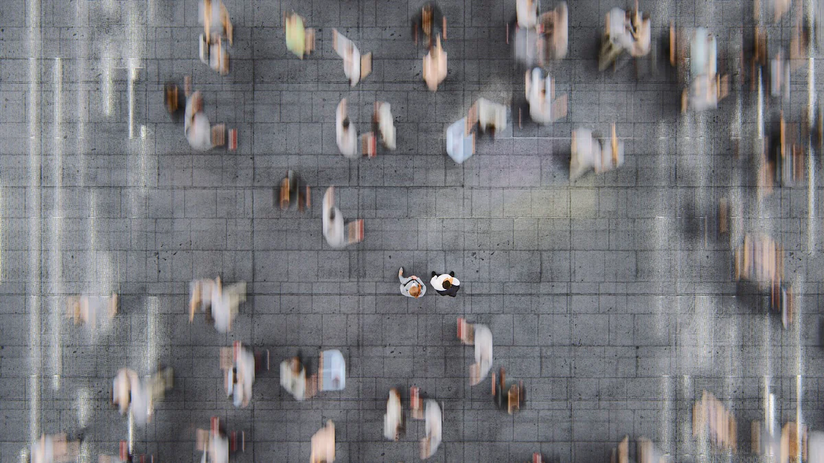 Invisible String Theory Symbolbild: zwei Menschen stehen in verschwommener Menschenmasse