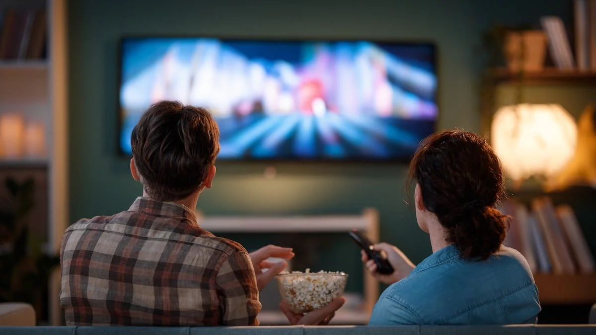 Strom: Glückliche Menschen schauen Fernsehen und essen Popcorn