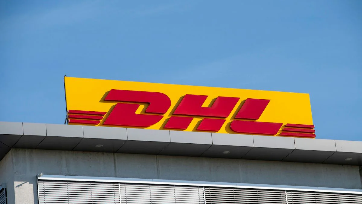 DHL-Logo auf einem Schild auf einem Gebäude vor blauem Himmel