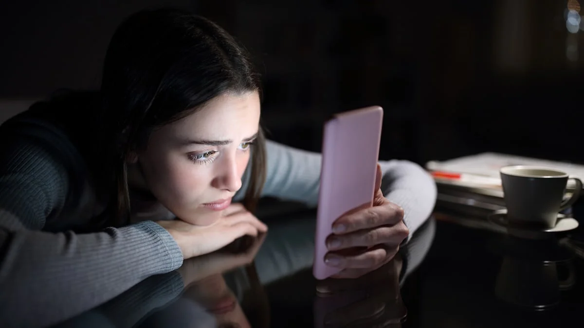 Fexting: Traurige junge Frau schaut auf ihr Handy