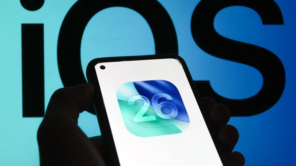 iOS 26 auf Smartphone vor iOS-Schriftzug im Hintergrund