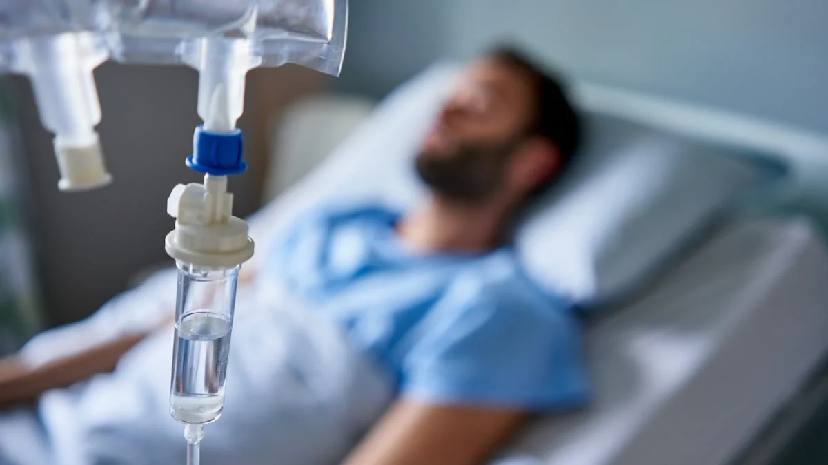 Mann landet wegen Gummibärchen im Krankenhaus: Junger Mann liegt mit Infusion in Krankenhausbett