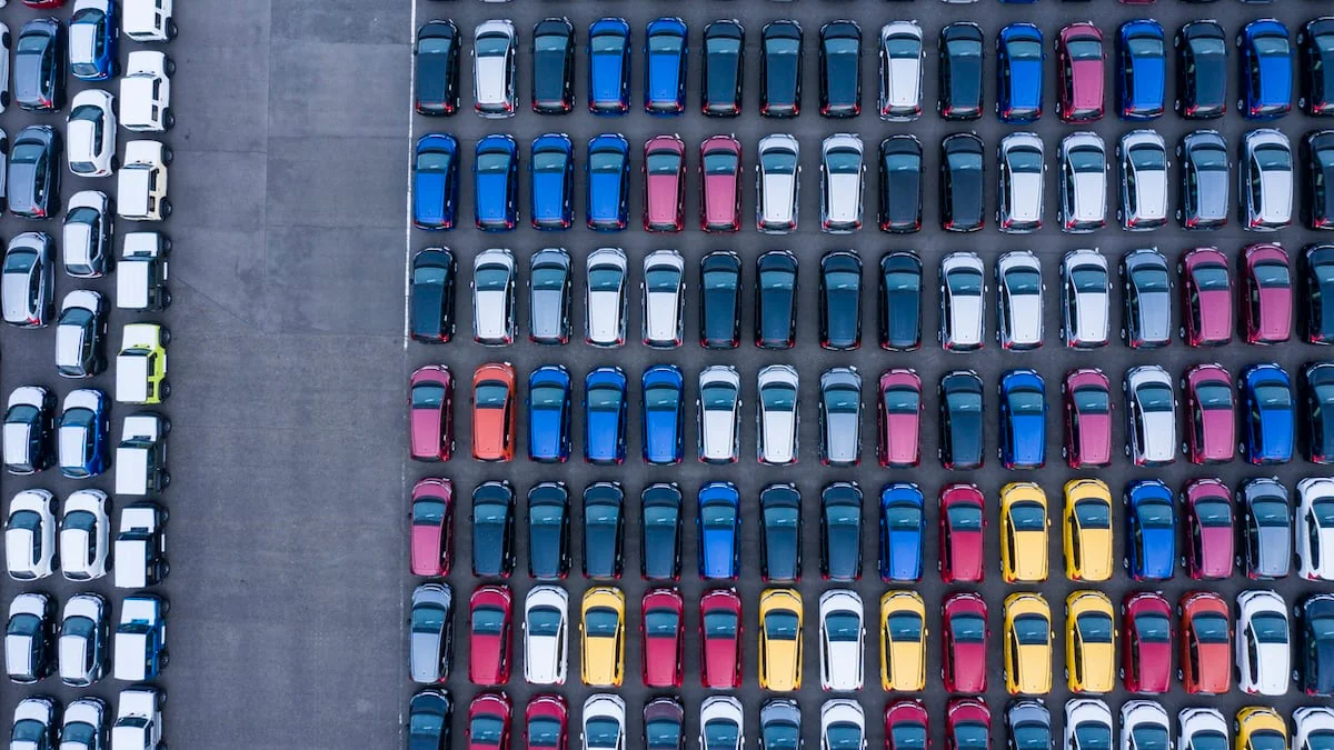 Autos in vielen verschiedenen Autofarben parken auf einem Parkplatz, das Ganze von oben fotografiert