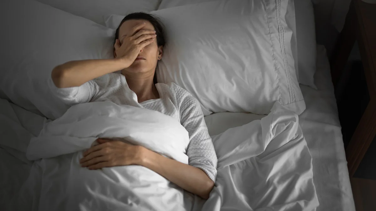 Auswirkungen von Kaffee auf den Schlaf: Frau hat Schlafprobleme und legt sich im Bett die Hand über das Gesicht