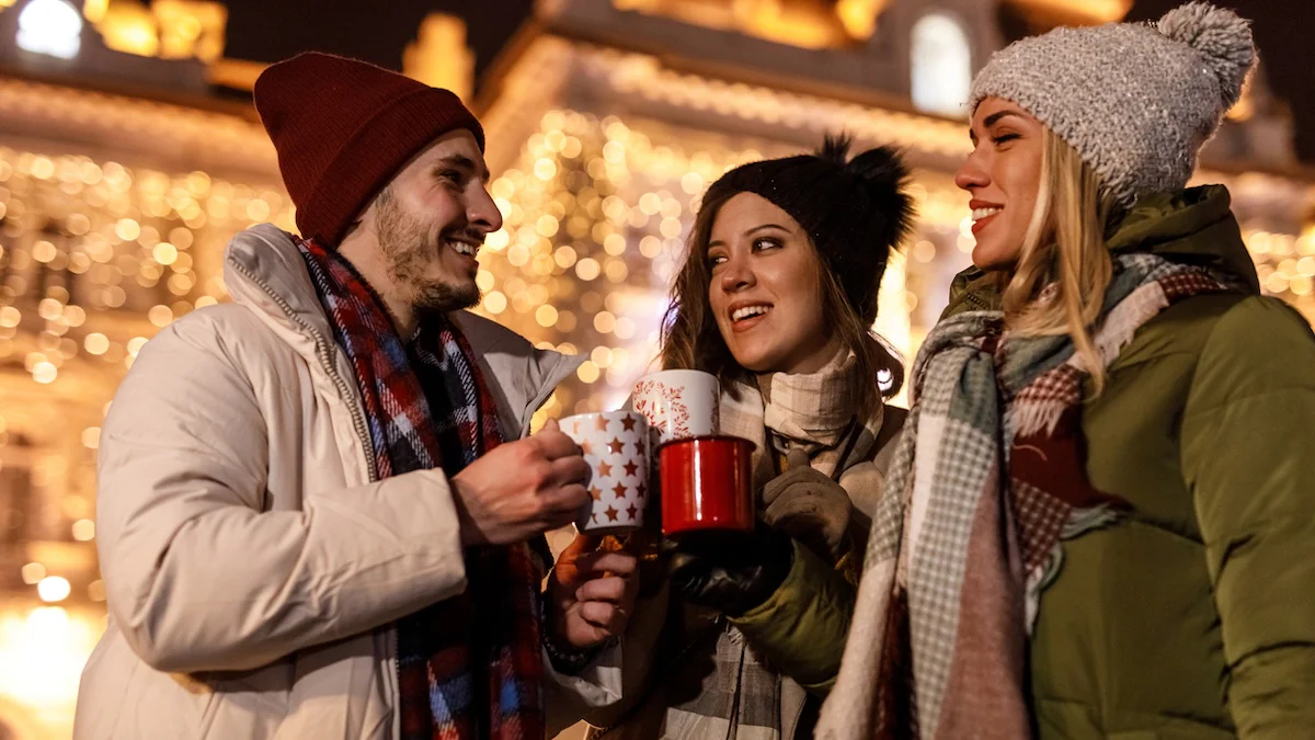 Zwei Frauen und ein Mann trinken zusammen auf einem Weihnachtsmarkt Glühwein