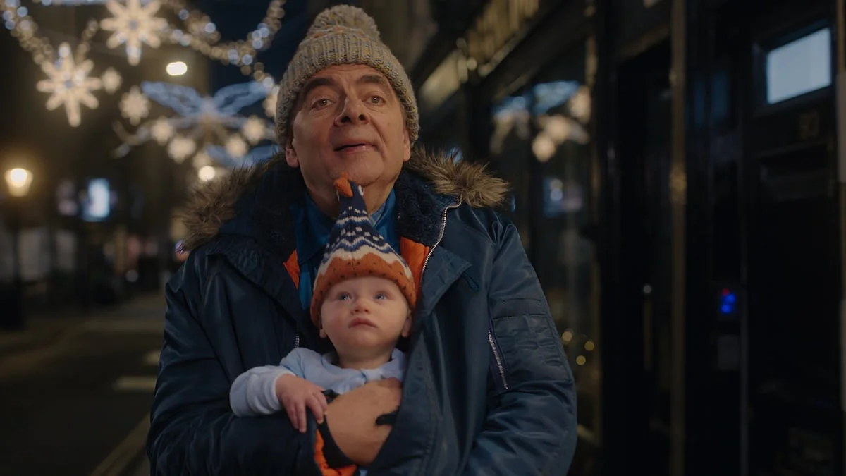 Szene aus der Netflix-Serie „Man vs Baby“ mit Rowan Atkinson, der ein Baby auf dem Arm hat